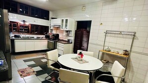 A modern kitchen with a dining area, featuring a ceiling fan, white tiled walls, and a black and white checkered floor. - Casa de Alto Padrão no Jd Marajoara (São Paulo)
