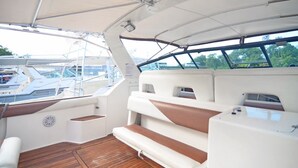 A boat's interior with seating, a steering wheel, and a view of other boats.