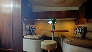 A compact, well-lit interior with two leather sofas, a small table with a plant, and a wooden floor.