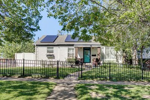 Une maison d’habitation dotée de panneaux solaires, d’une porte verte et d’une clôture noire.