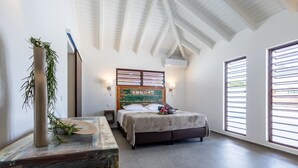 Ein Schlafzimmer mit einem Bett, einem Nachttisch mit Pflanze, einer Wand-Klimaanlage und einem Fenster mit Jalousien.