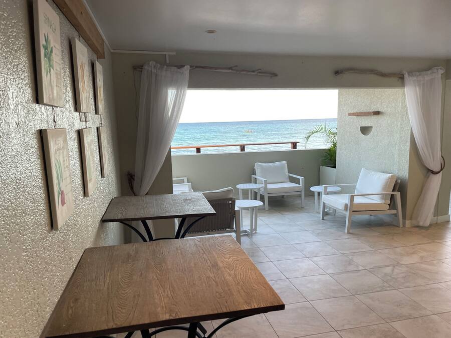 Un balcón con vista al mar, amoblado con sillas y una mesa blancos.