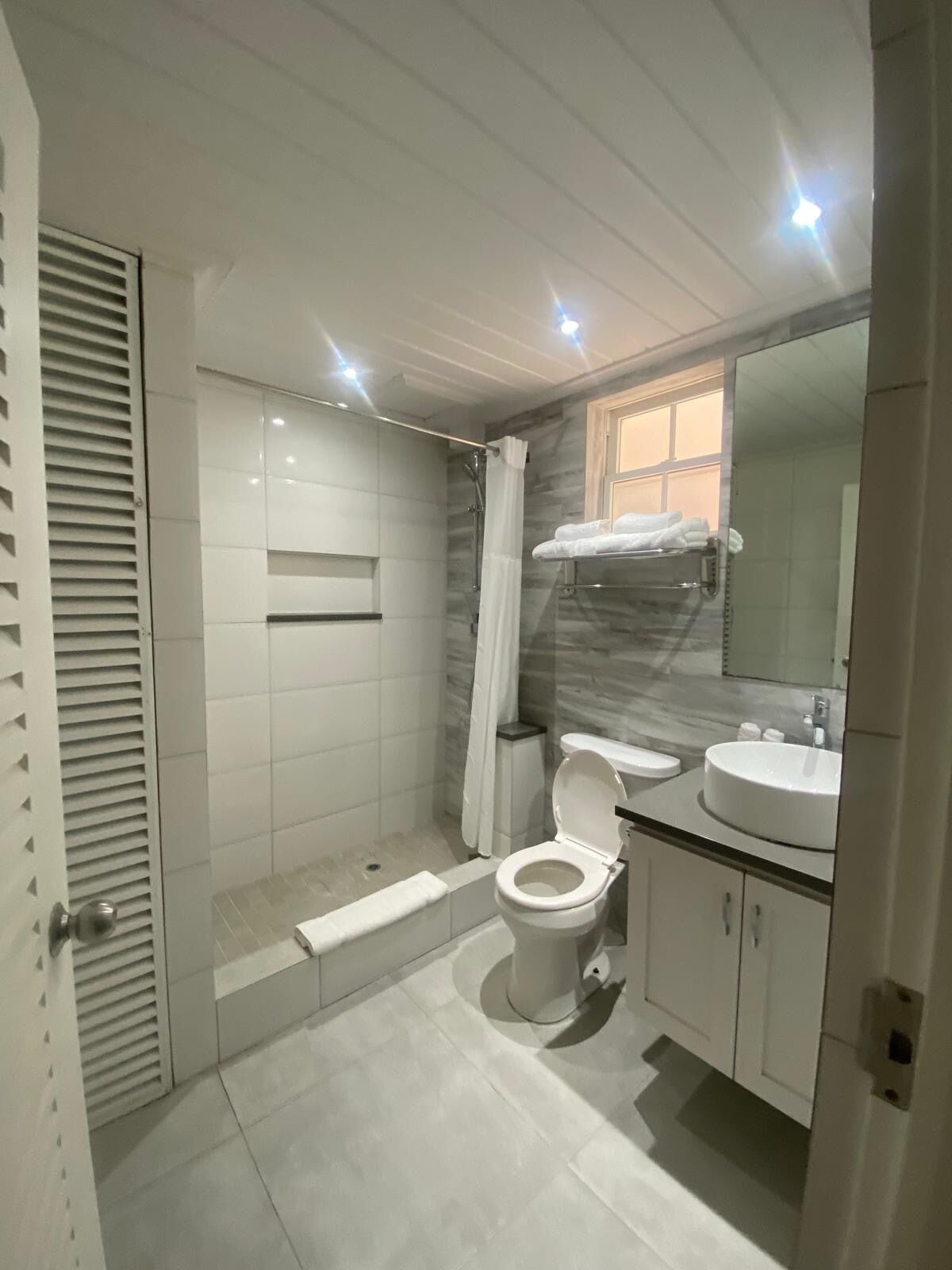 Un baño moderno con cabina de ducha, inodoro, lavabo y espejo.