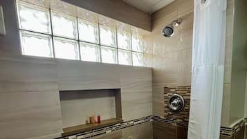 Un bagno con doccia, una finestra vista e uno scaffale con articoli da toilette.