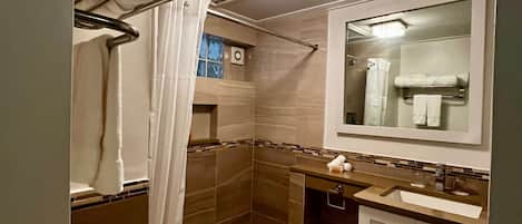 Een badkamer met douche, toilet, wastafel en spiegel.