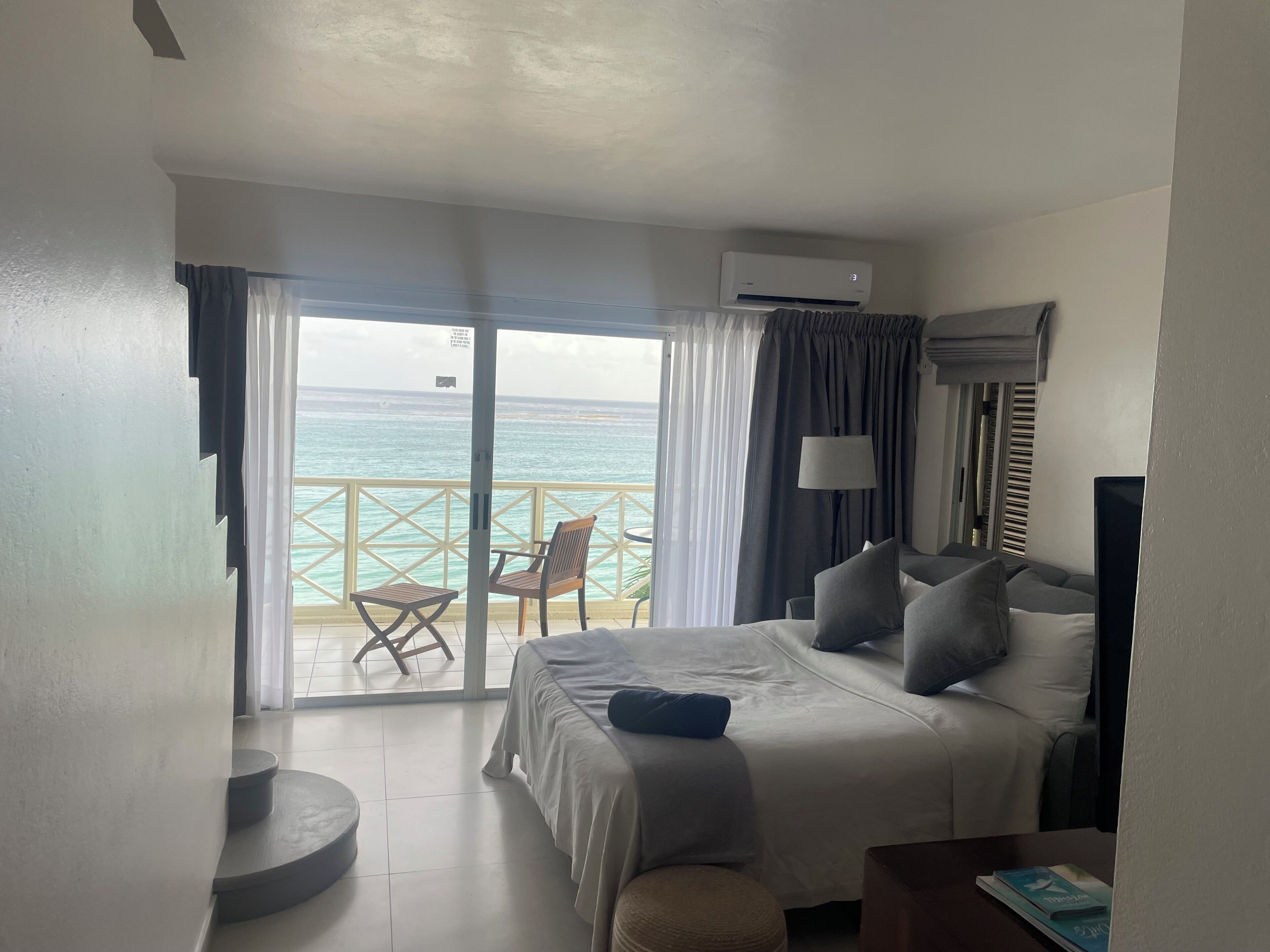 Una habitación de hotel con cama, televisión, lámpara y vista al océano.