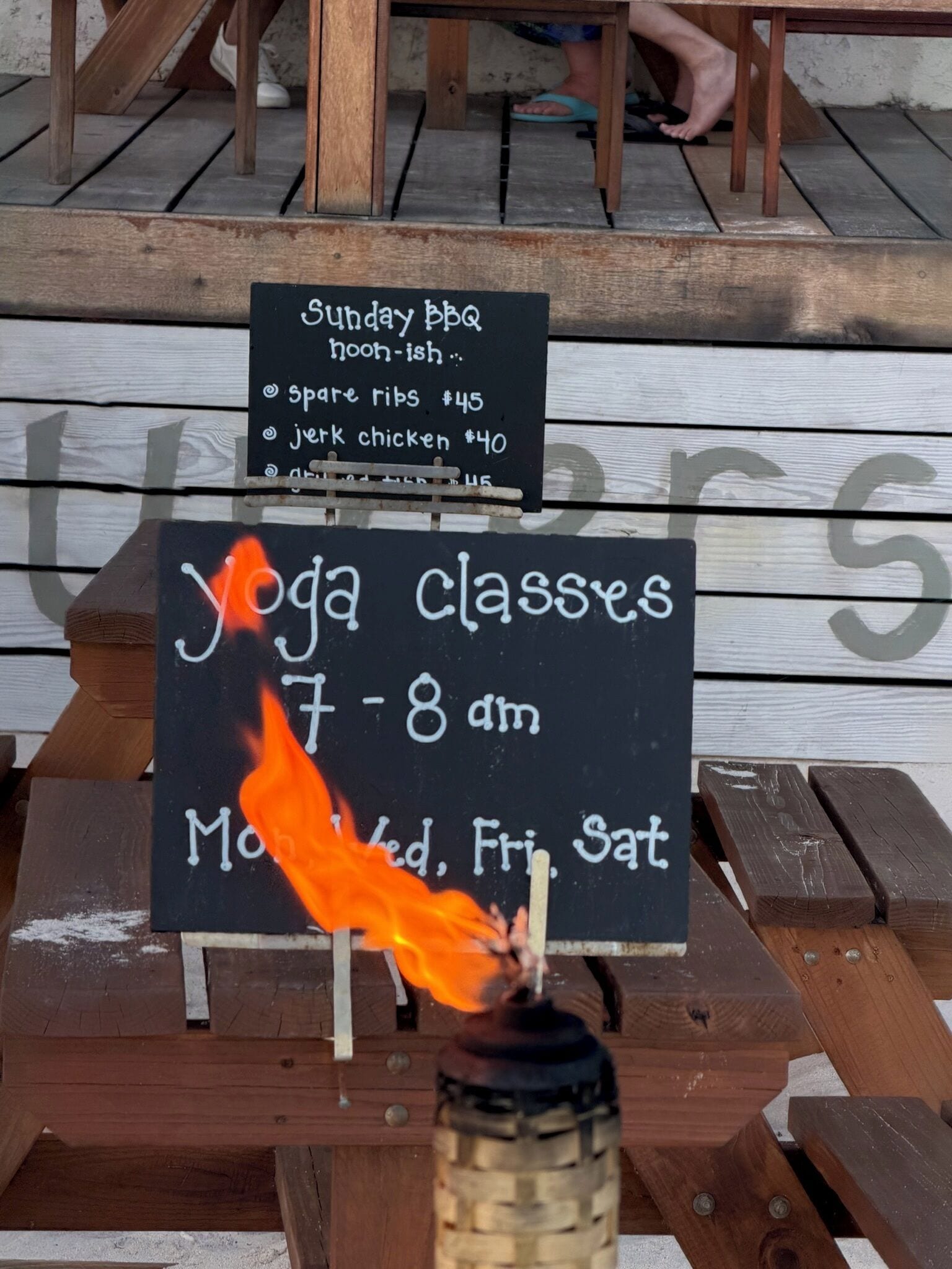 A wooden deck with signs advertising Sunday BBQ and yoga classes.