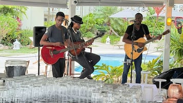 A bar area with a pool view, a stage with musicians, and a caution sign on the counter.