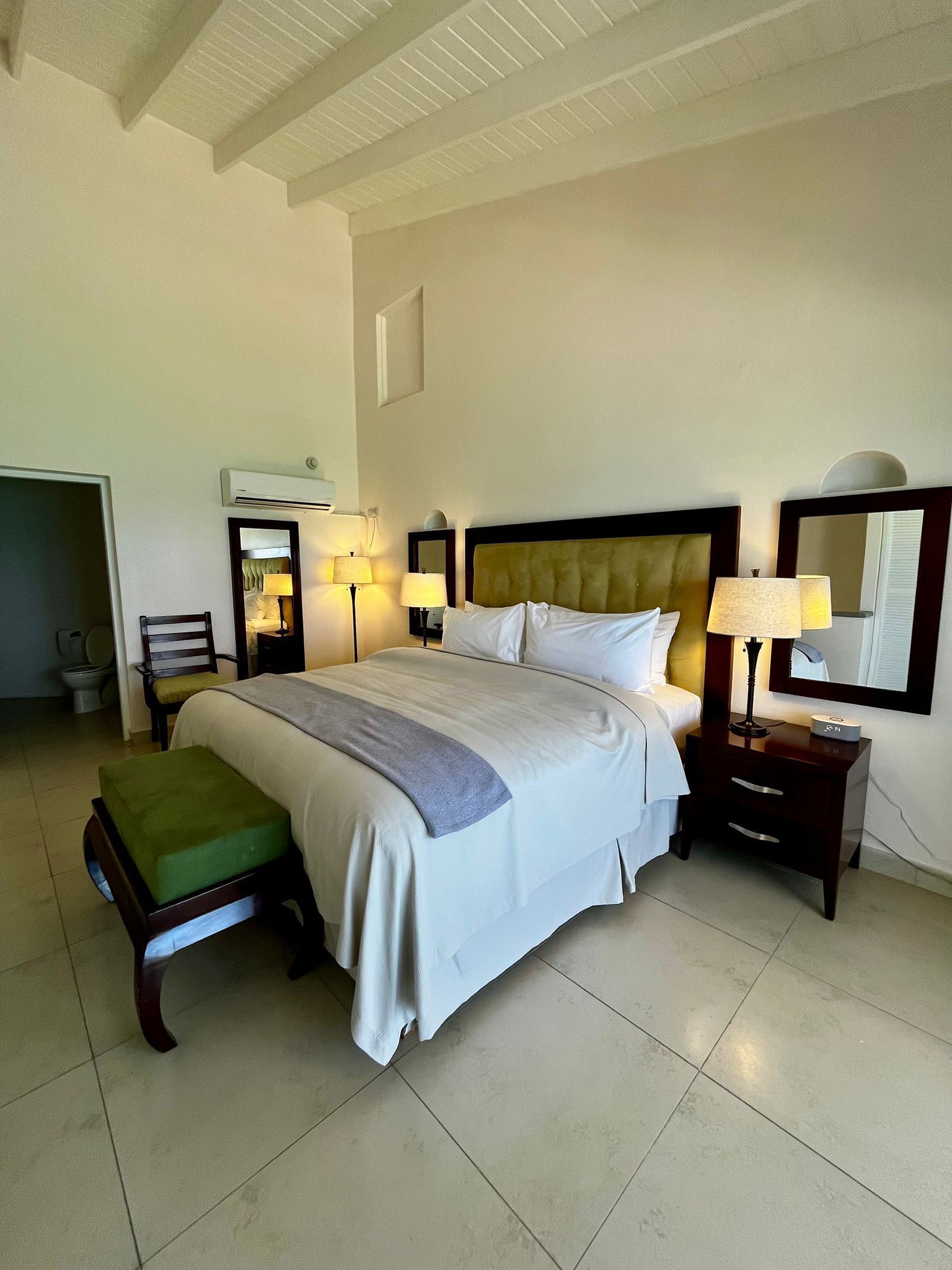 Une chambre d’hôtel avec un grand lit, une table de chevet avec une lampe, une chaise et une petite table également équipée d’une lampe.