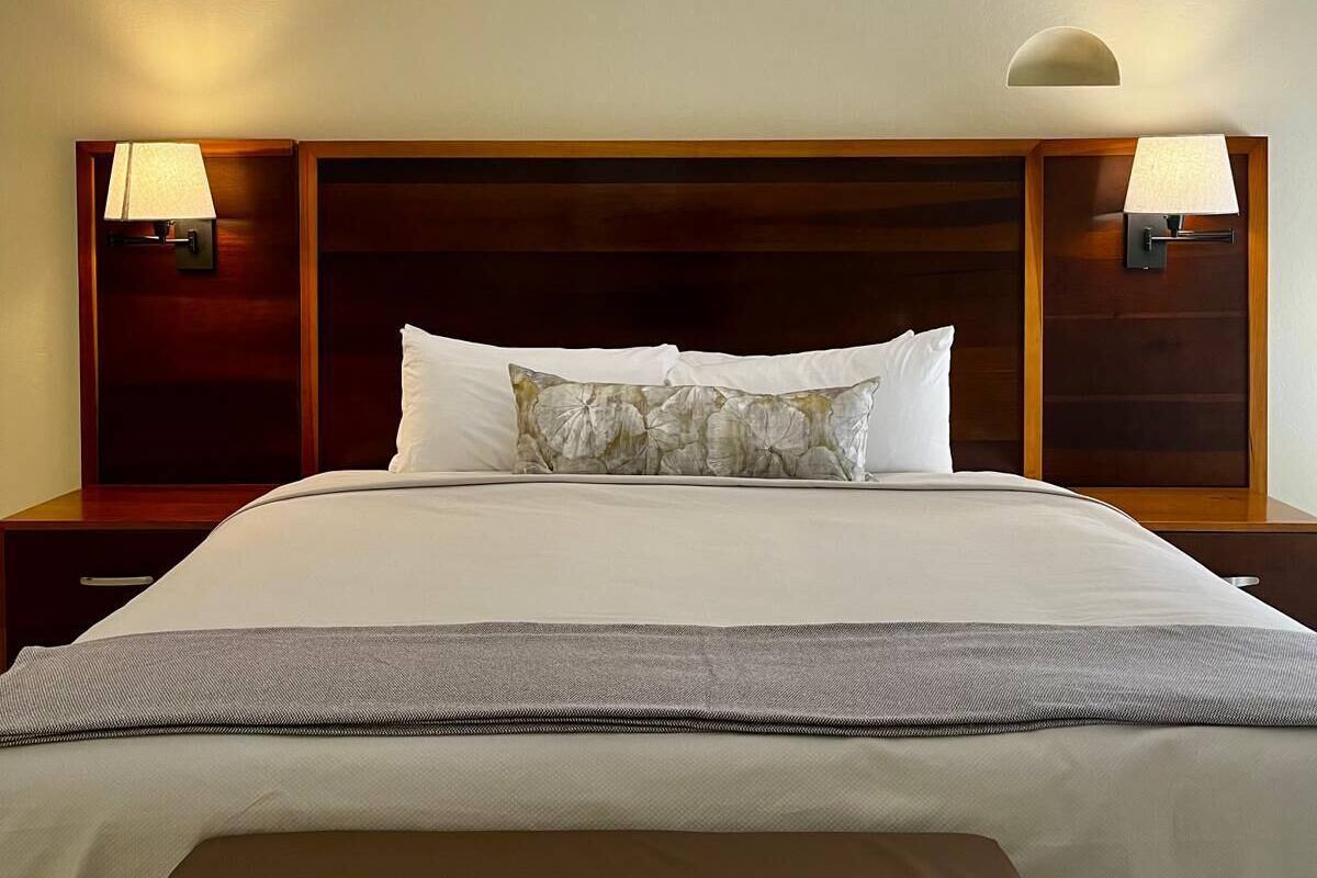 Ein Hotelzimmer mit einem großen Bett, zwei Nachttischen mit Lampen und einem Kopfteil mit integriertem Regal.