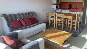 A cozy living room with a sofa, a coffee table, and a dining area with chairs and a table. - 1st floor, tv, 52m², Alpe d'Huez (L'Alpe d'Huez)