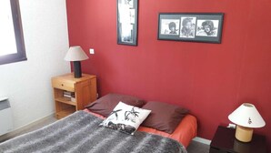 A bedroom with a bed, a nightstand, a lamp, and two framed pictures on the wall. - 1st floor, tv, 52m², Alpe d'Huez (L'Alpe d'Huez)