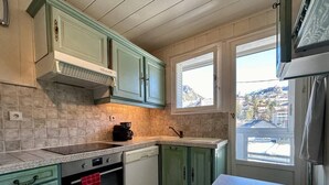 Una cocina con gabinetes verdes, estufa, horno y lavavajillas.