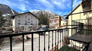 Un hotel con balcón que da a una calle y una montaña.