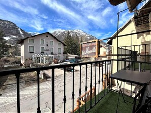 Un hotel con balcón que da a una calle y una montaña.