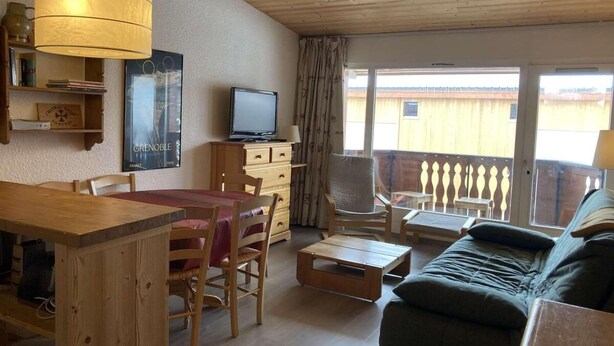 A cozy room with a wooden dining table, chairs, a sofa, and a TV. - 2nd floor, balcony, tv, ski locker, 52m², Alpe d'Huez (L'Alpe d'Huez)
