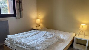 A neatly made bed with white bedding, two bedside lamps, and a window with curtains. - 2nd floor, balcony, tv, ski locker, 52m², Alpe d'Huez (L'Alpe d'Huez)
