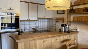 A kitchen with wooden cabinets, a built-in oven, a tiled backsplash, and a hanging light fixture. - 2nd floor, balcony, tv, ski locker, 52m², Alpe d'Huez (L'Alpe d'Huez)