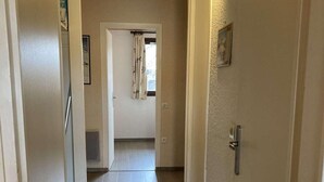 A narrow hallway with light-colored walls and wooden flooring, leading to a room with a window and a door. - 2nd floor, balcony, tv, ski locker, 52m², Alpe d'Huez (L'Alpe d'Huez)