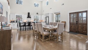 Una cocina amplia con una isla grande, armarios blancos y un comedor con seis sillas.