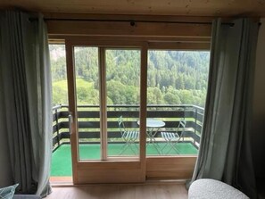 Ein Zimmer mit Balkon und Blick auf ein bewaldetes Gebiet.