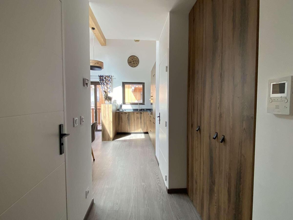 A hallway leading to a kitchen with wooden cabinets and a built-in oven.