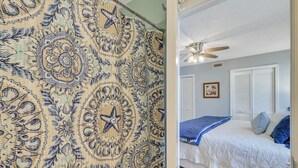 Una camera da letto con un letto, una ventola a soffitto e una finestra con persiane.