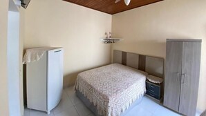 A bedroom with a bed, a wardrobe, a ceiling fan, and a refrigerator. - Two suites just 100 meters from the central square and 20 km from Pedra do Baú. (São Bento do Sapucaí)