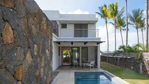 A modern two-story house with a stone exterior, a swimming pool, and a patio with outdoor furniture. - Unique Villa Feet in the water-pool- Grand Baie (Grand Baie)