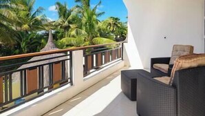 A balcony with a wicker sofa and a view of palm trees. - To complete (Cap Malheureux)