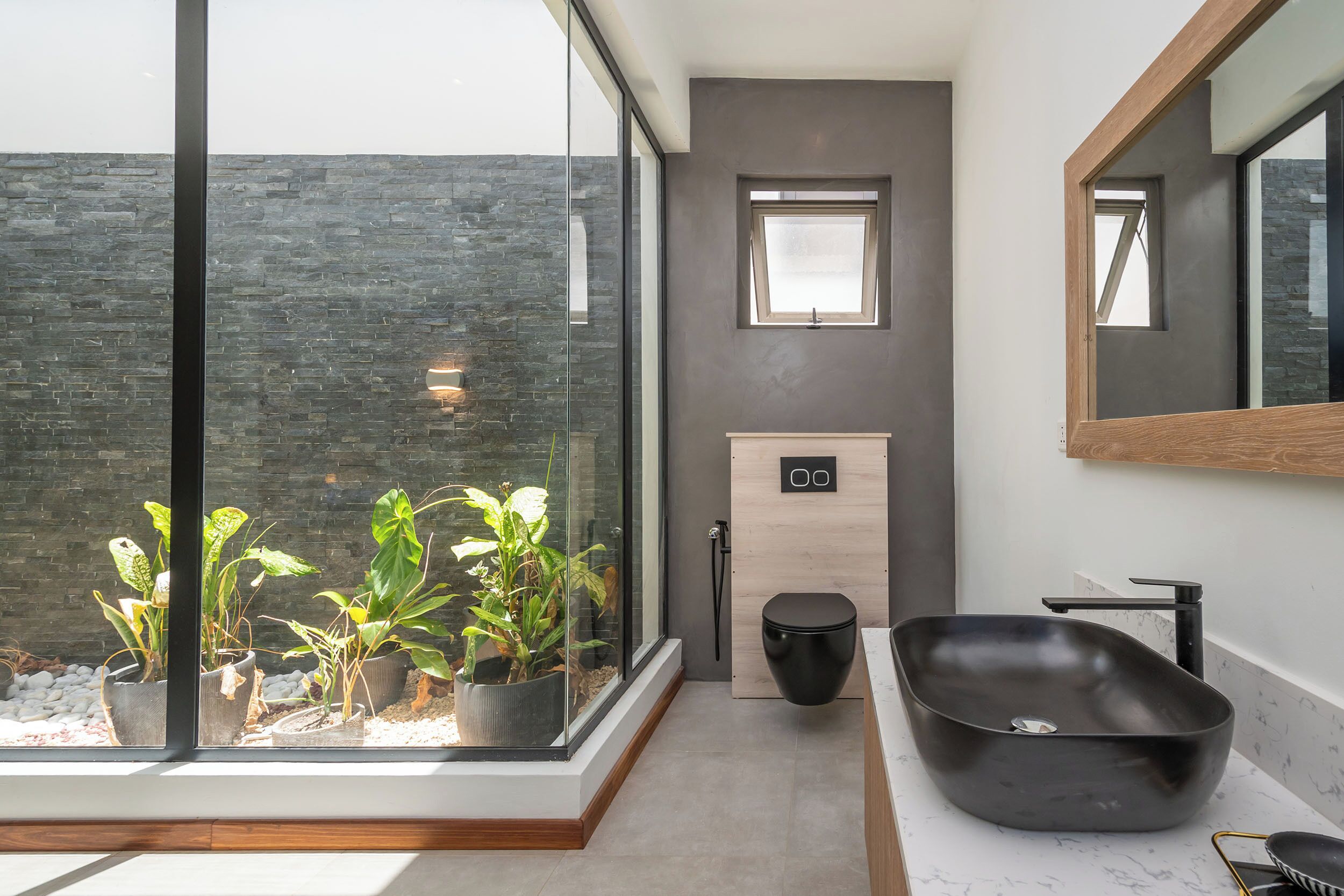Un bagno moderno con un'ampia finestra, un lavabo nero e un mobile contenitore in legno.