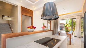 Une cuisine moderne dotée d’un îlot central, d’une cuisinière intégrée et d’une hotte aspirante de grande taille placée au-dessus.