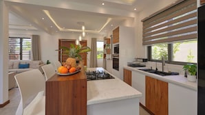 Cocina moderna con una isla central, horno empotrado y un amplio ventanal con persianas.