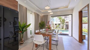 Un comedor moderno con una mesa de madera, sillas blancas y vistas a una piscina.