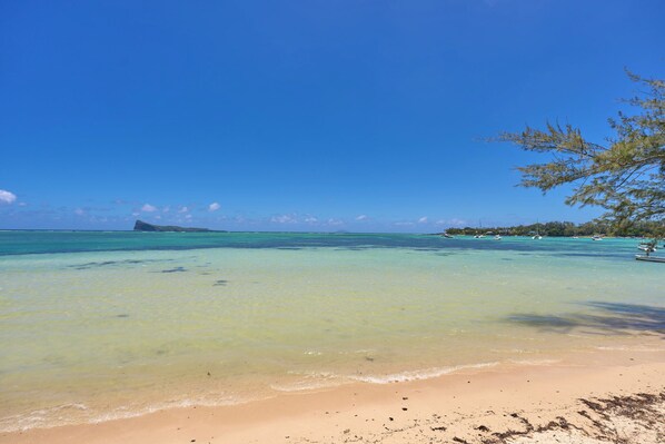 A beach with clear turquoise water, a sandy shore, and a distant island.