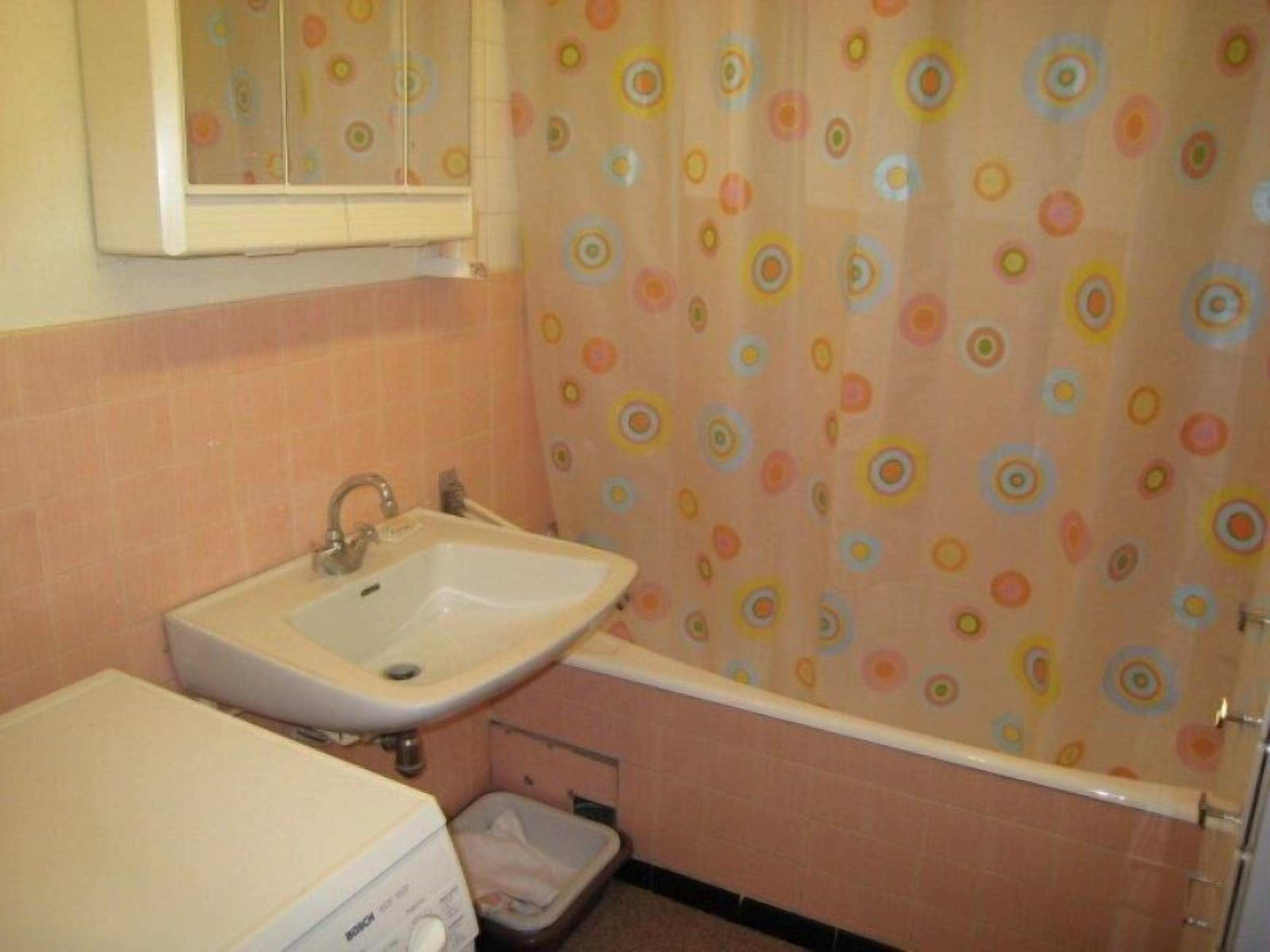 Een badkamer met een wastafel, toilet en een douchegordijn met een kleurrijk rond patroon.