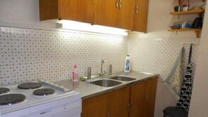 A kitchen with a stove, two sinks, wooden cabinets, and a tiled backsplash.