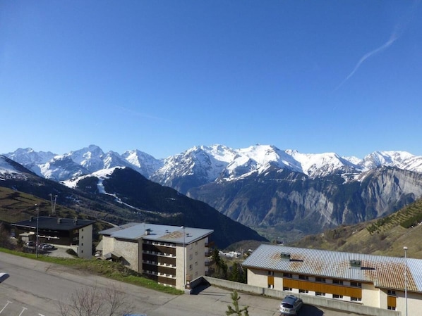 A building with a parking lot and a view of snow-capped mountains.