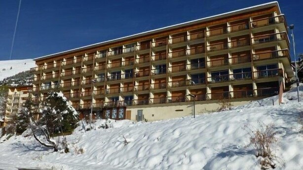 A multi-story hotel with a wooden facade and balconies.