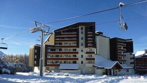 Un hôtel à plusieurs étages, avec un télésiège visible en arrière-plan.