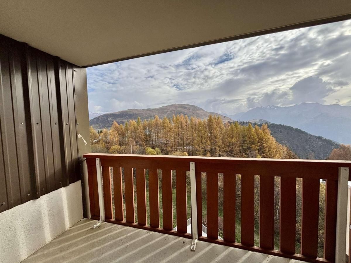 Un balcon avec vue sur les arbres aux couleurs automnales et les montagnes.