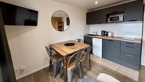 Une cuisine de taille réduite comprenant une table à manger, des chaises, un four à micro-ondes et un évier.