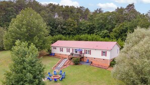 A two-story house with a red roof, surrounded by a well-maintained lawn and trees. - King Bed Pet Friendly BBQ Grill Peaceful (Madison)
