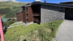 Un edificio con fachada de piedra y niveles superiores de madera, con montañas al fondo.