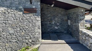 Un edificio de piedra con techo de metal, un letrero de madera y una puerta de metal.