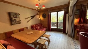 Una habitación acogedora con una mesa de madera, bancos, un sofá y una ventana con cortinas.