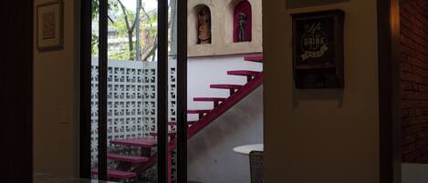 A modern interior with a staircase, a dining area, and a view through a glass door.