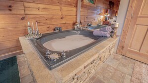 Une baignoire en pierre avec un intérieur en bois, une serviette et des articles de toilette disposés sur un plateau.