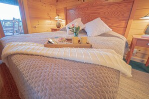 Una camera accogliente in legno con un letto grande, un comodino con una lampada e una finestra vista esterna.