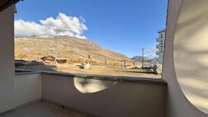 A balcony with a view of a mountainous landscape, a building labeled "LE CHAIX," and a clear sky. - 100m from shops, 1st floor, balcony, tv, ski locker, 52m², Alpe d'Huez (L'Alpe d'Huez)